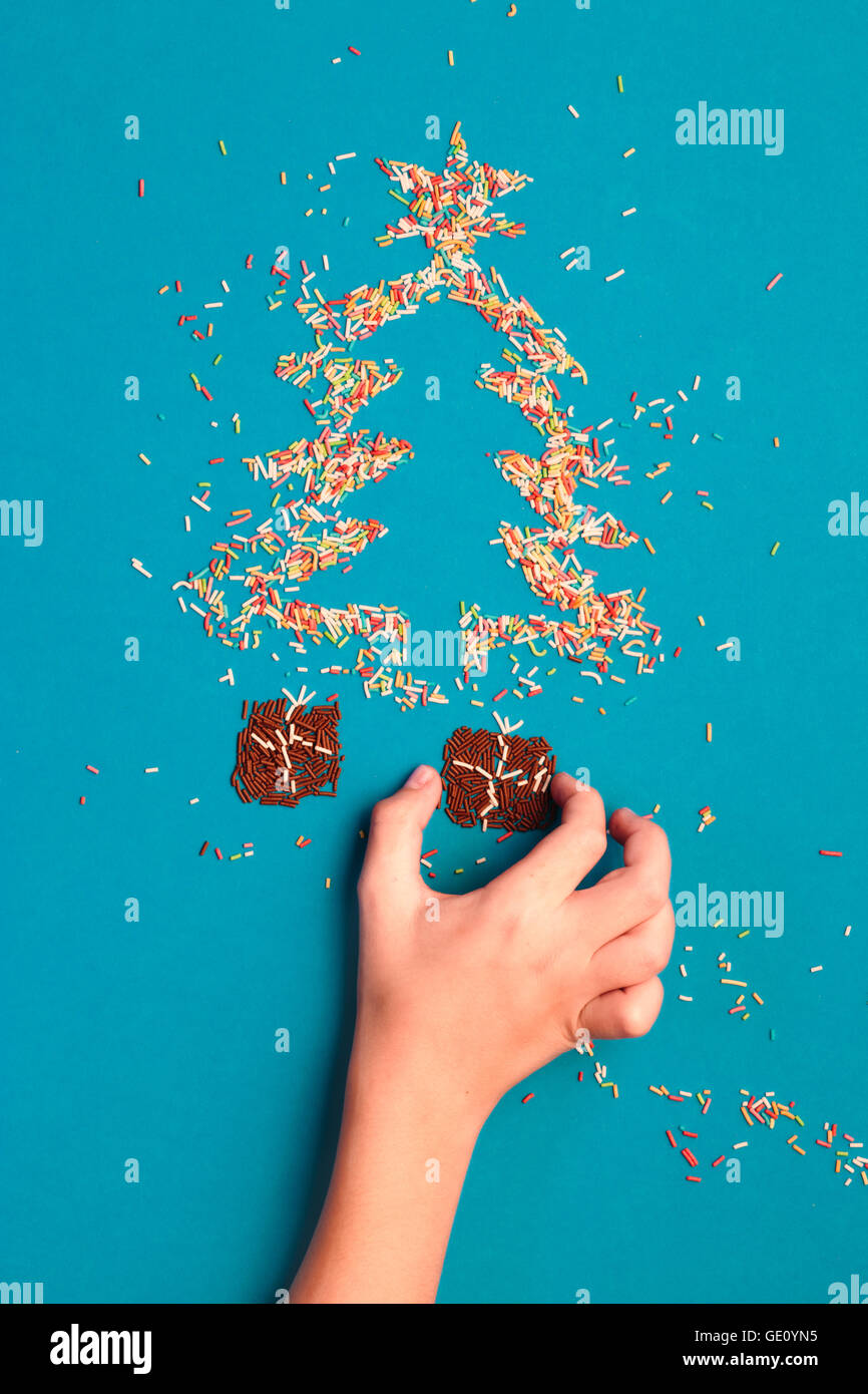 Symbole der Weihnachtsbaum und Geschenke gemacht von bunten Streuseln auf blauem Hintergrund Stockfoto