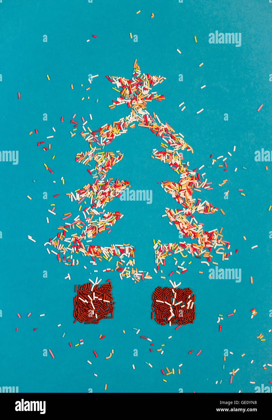 Symbole der Weihnachtsbaum und Geschenke gemacht von bunten Streuseln auf blauem Hintergrund Stockfoto