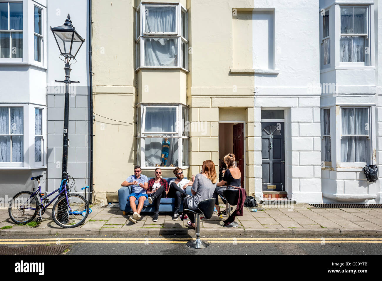 Junge Leute sitzen auf der Straße vor ihrem Haus an einem Sommernachmittag in Brighton. Stockfoto