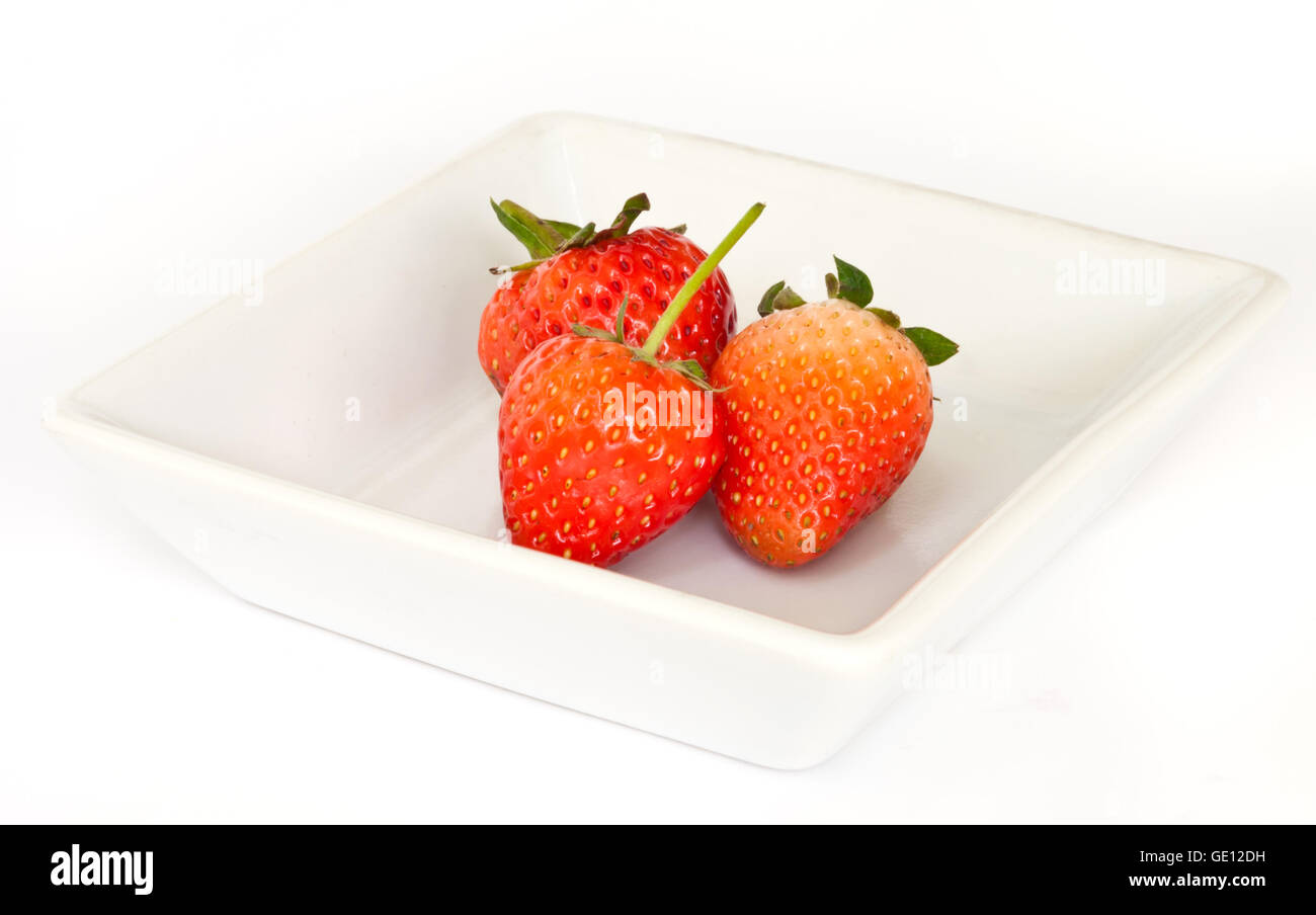 rote, reife Erdbeeren auf einem weißen Teller. Stockfoto