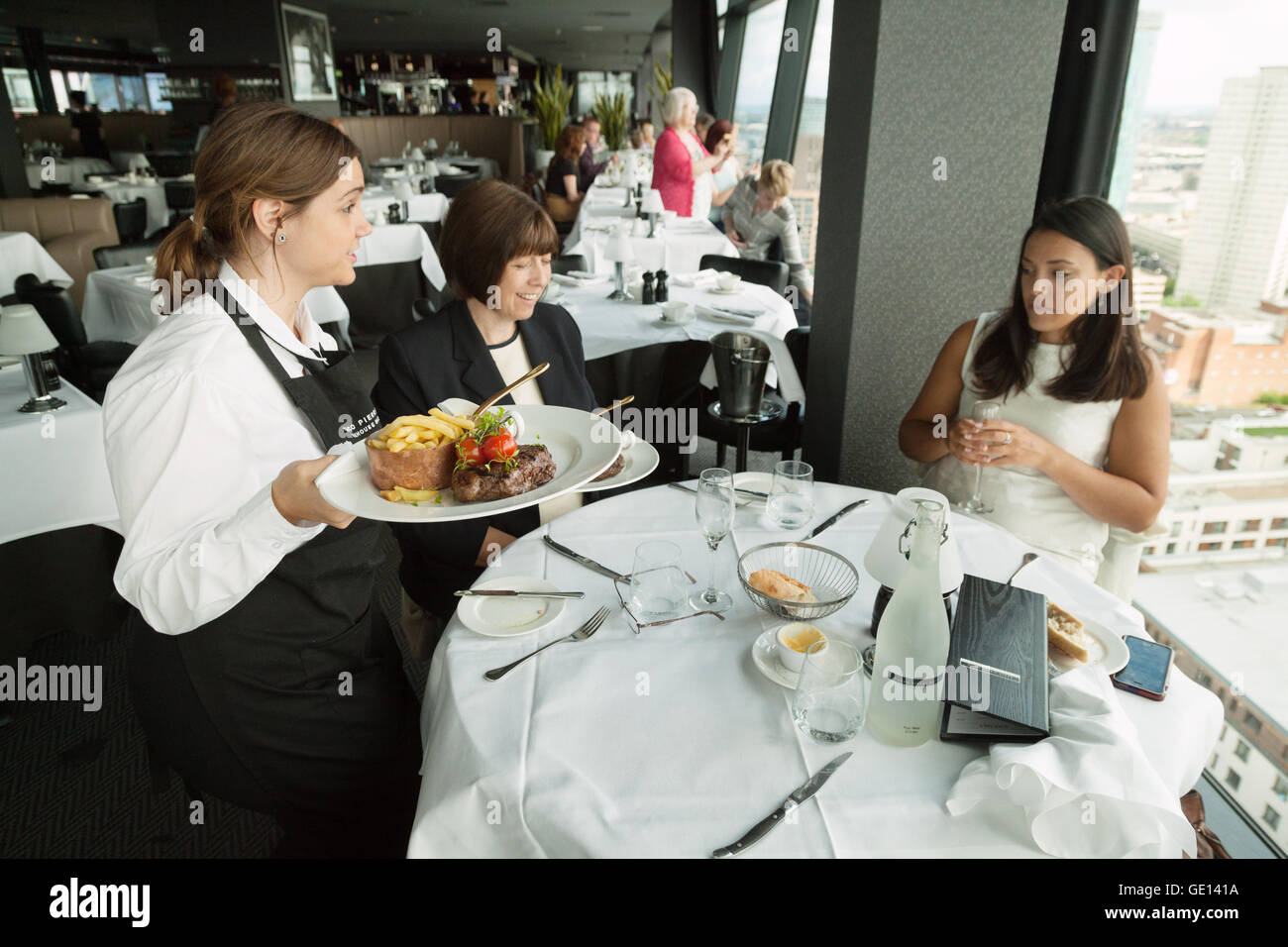 Kellnerin UK; Kellnerin, die den Kunden Speisen serviert, Marco Pierre White Steakhouse, The Cube, Birmingham UK Stockfoto