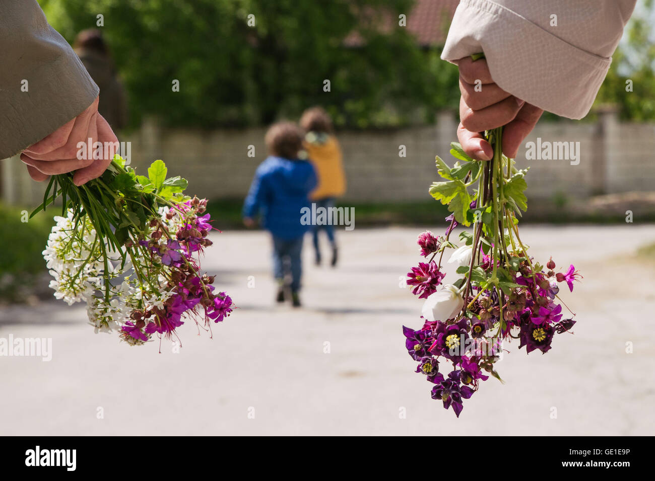 Zwei Frauen und zwei Jungs gehen für einen Spaziergang mit Blumen Stockfoto
