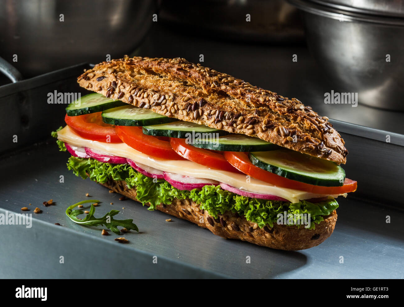 Sandwich mit Käse, Tomaten, Gurken, Radieschen und Salat. Dunkel und launisch. Stockfoto