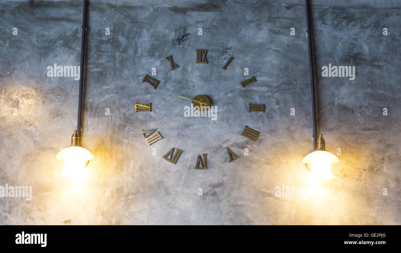 Betonmauer mit Vintage Uhr und Glühbirnen Stockfoto