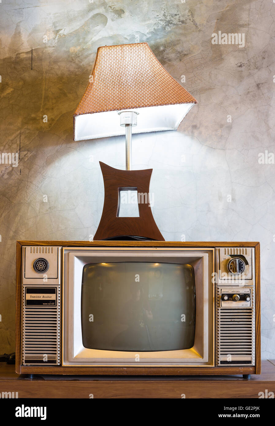 Retro-tv mit Holzkasten und Laterne in Raum mit Vintage Tapete auf Holztisch Stockfoto