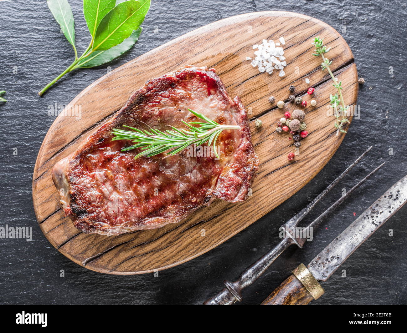 Mittlere Rib-Eye Steak mit Gewürzen auf dem Tablett aus Holz. Stockfoto