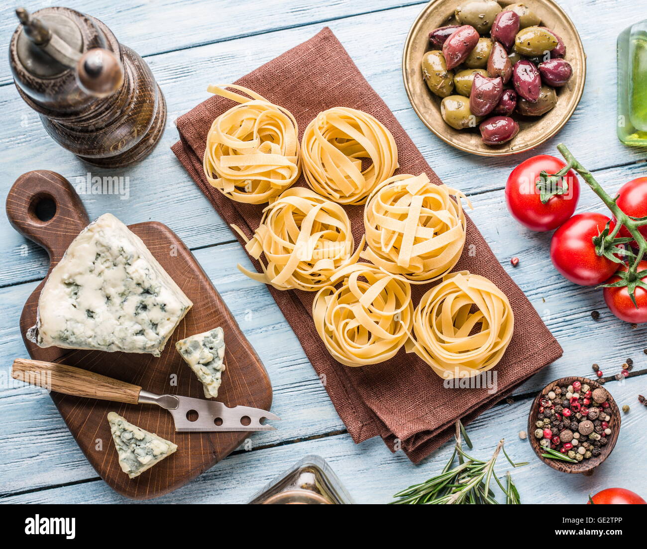 Pasta Zutaten. Cherry-Tomaten, Spaghetti Nudeln, Rosmarin und Gewürze auf dem Holztisch. Stockfoto