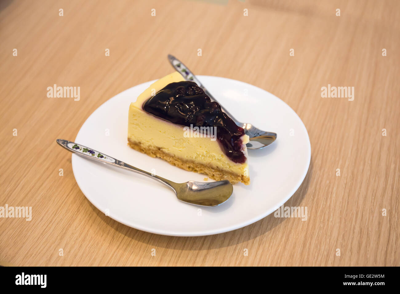 Blaubeer-Käsekuchen mit kleinen Löffel in den Teller auf Holztisch Stockfoto