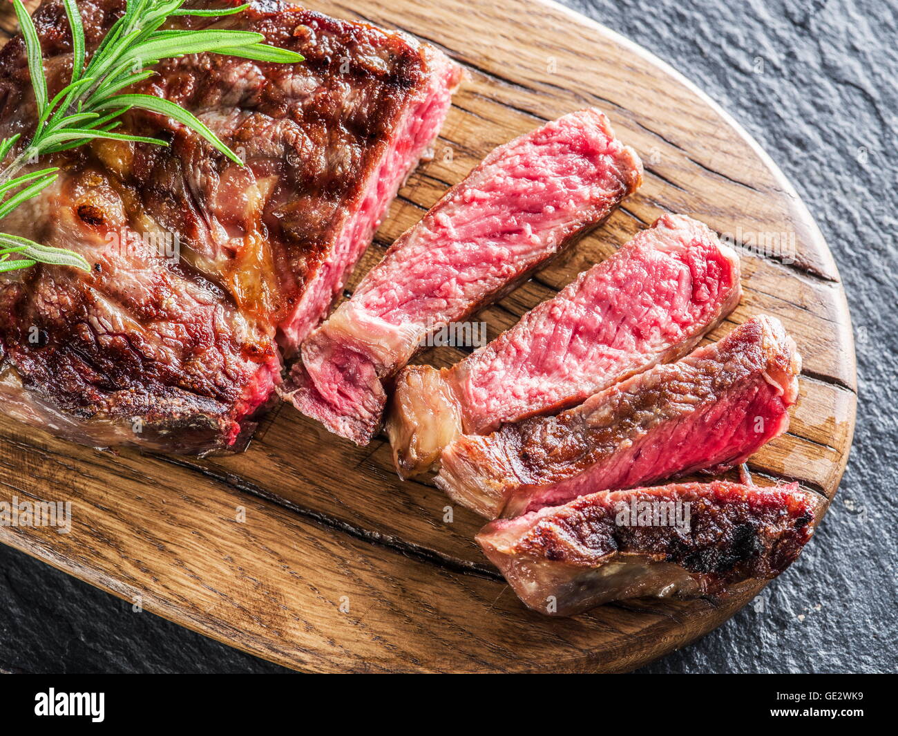 Mittlere Ribeye-Steak mit Gewürzen auf dem Tablett aus Holz. Stockfoto