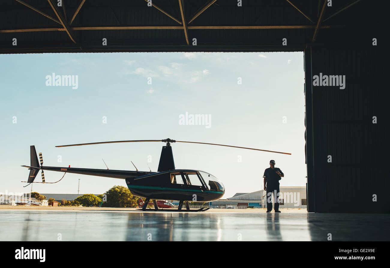 Voller Länge Bild der Pilot mit einem Hubschrauber in einem Flugzeughangar. Stockfoto