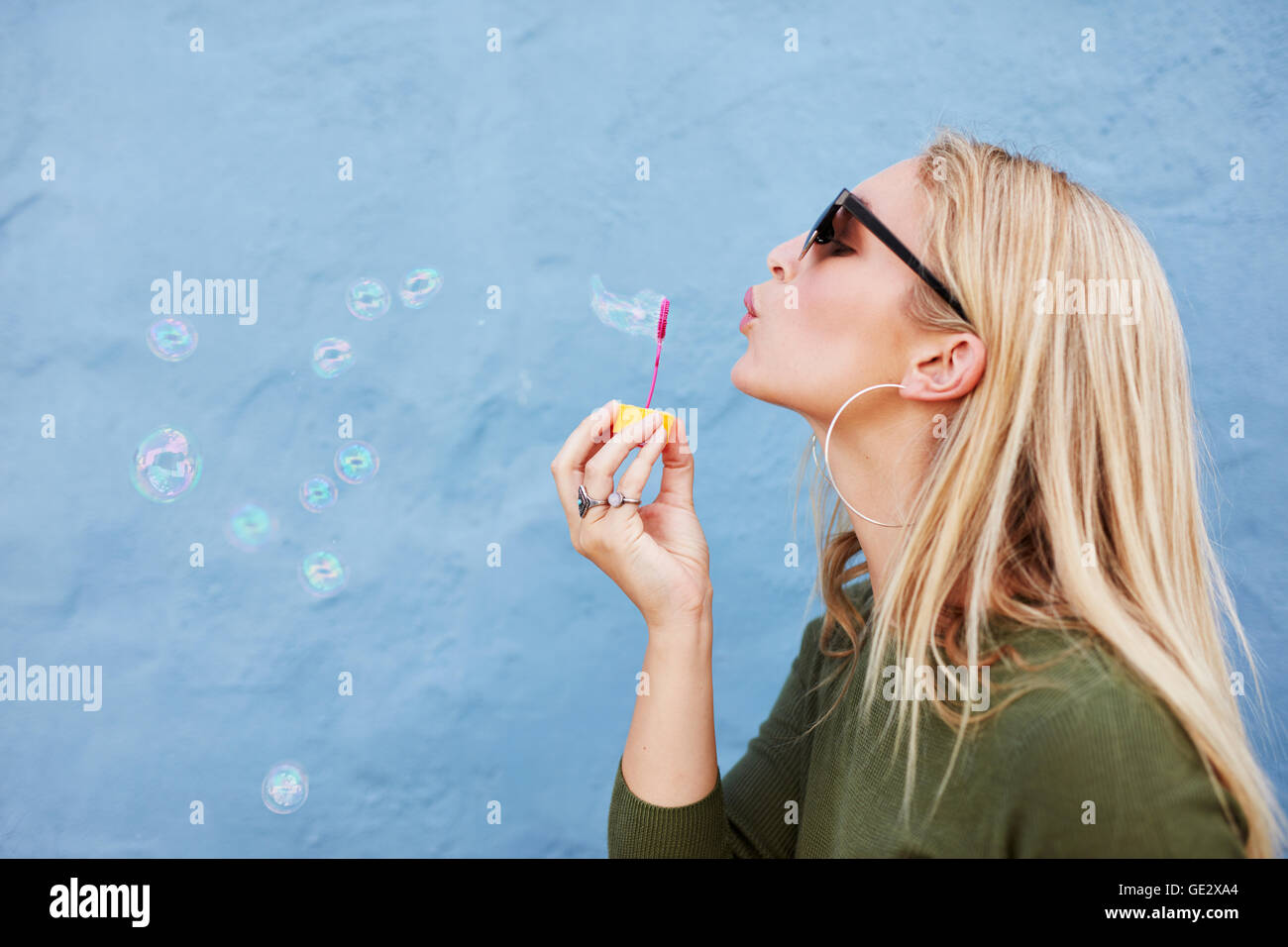 Richtungskontrolle Ansicht von attraktiven weiblichen Modell Seifenblasen. Junge Frau mit Spaß vor blauem Hintergrund. Stockfoto