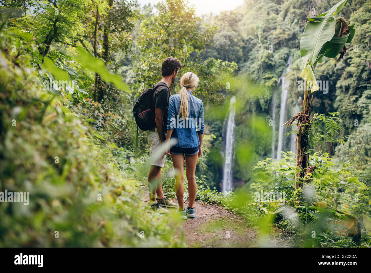 Rückansicht des junges Paar auf der Suche am Wasserfall. Zwei Wanderer im Wald stehen und Wasserfall anzeigen. Stockfoto