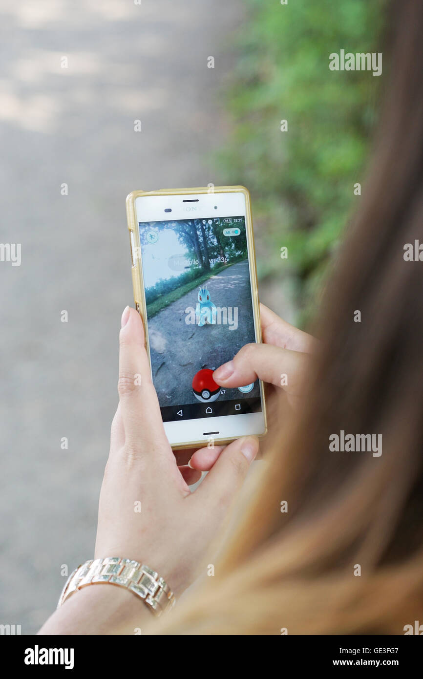 Mädchen spielen Pokemon unterwegs auf ihrem smartphone Stockfoto