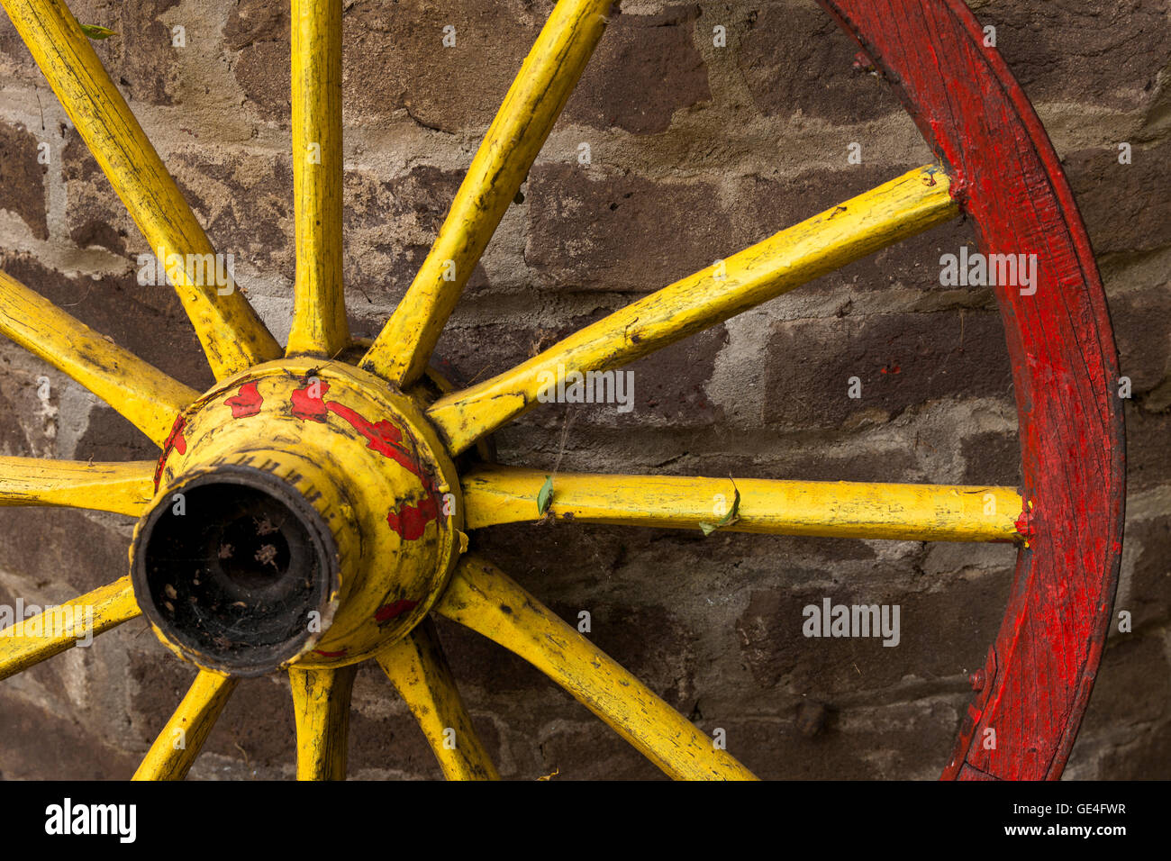 Detail der alten Wagenrad mit Metallrand stützte sich auf einer Steinmauer Stockfoto