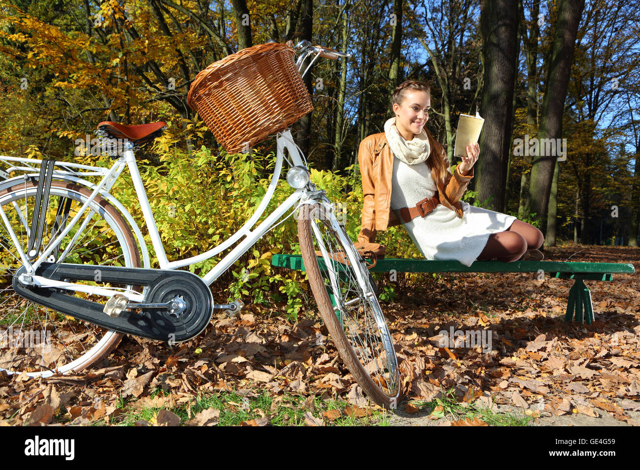 Schöne Frau im Herbst Landschaft auf einer Parkbank Stockfoto