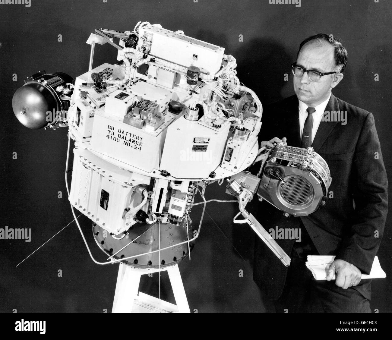 Raymond J. Rulis, SERT-1-Programm-Manager erscheint hier untersuchen die SERT-1 Sonde nach seiner Ankunft am NASA Lewis Research Center zu Testzwecken vor dem Flug. Die Lewis gebauten Ion-Motor vor Mr Rulis, und Hughes-Motor, im Vakuum-Pod ist ist auf der anderen Seite. Lewis bekannt jetzt als John H. Glenn Research Center.  Bild-Nr.: 64-SERT-ich-11 Stockfoto