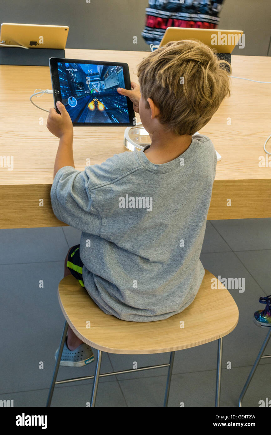 Ein kleiner Junge ca. 7-8 Jahre alt spielt ein Spiel auf dem iPad im Apple Store in Santa Barbara, Kalifornien. Stockfoto