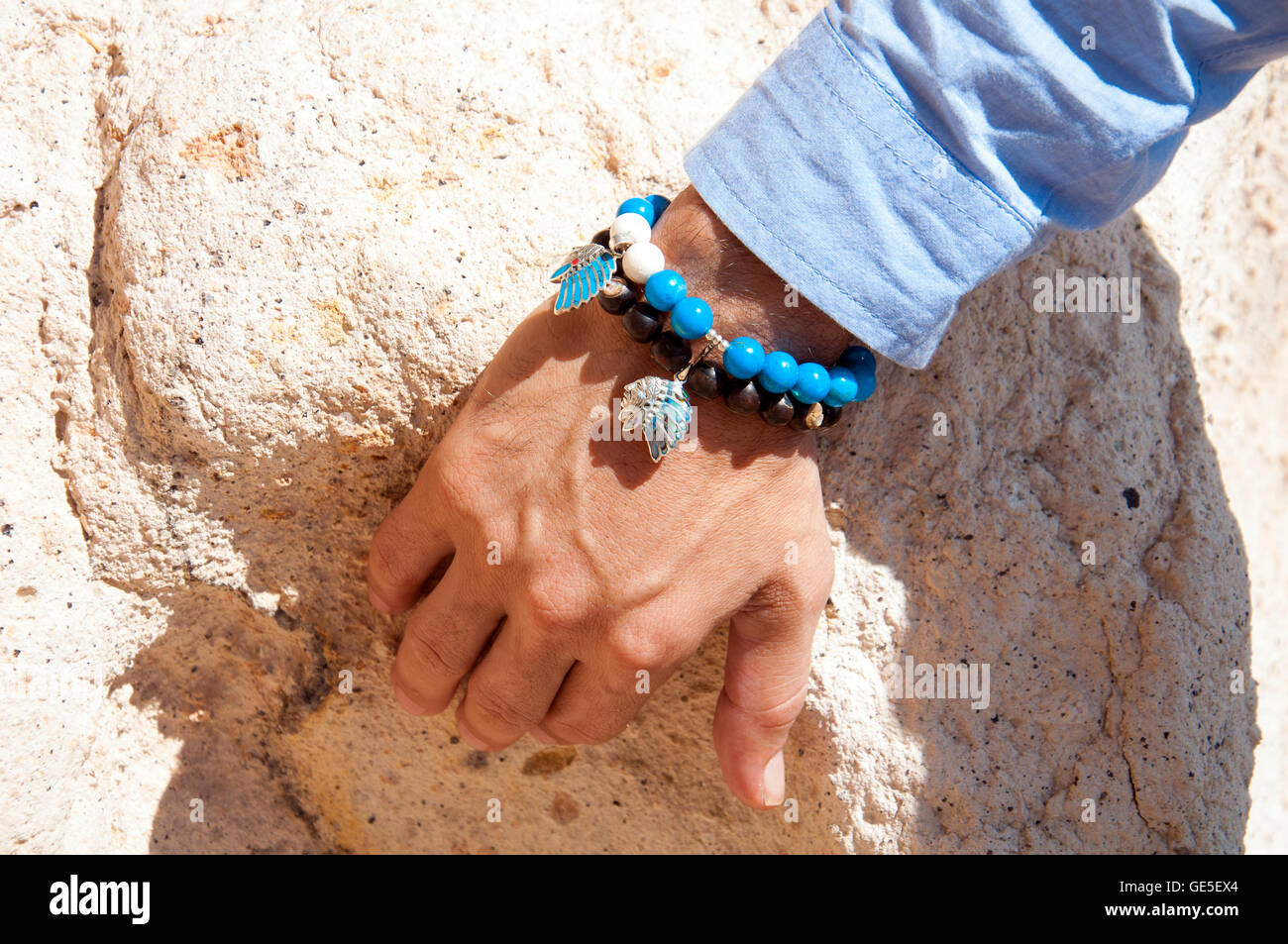 Männliche Hand mit blauen Perlen Armbänder mit blauem Hemd Stockfoto