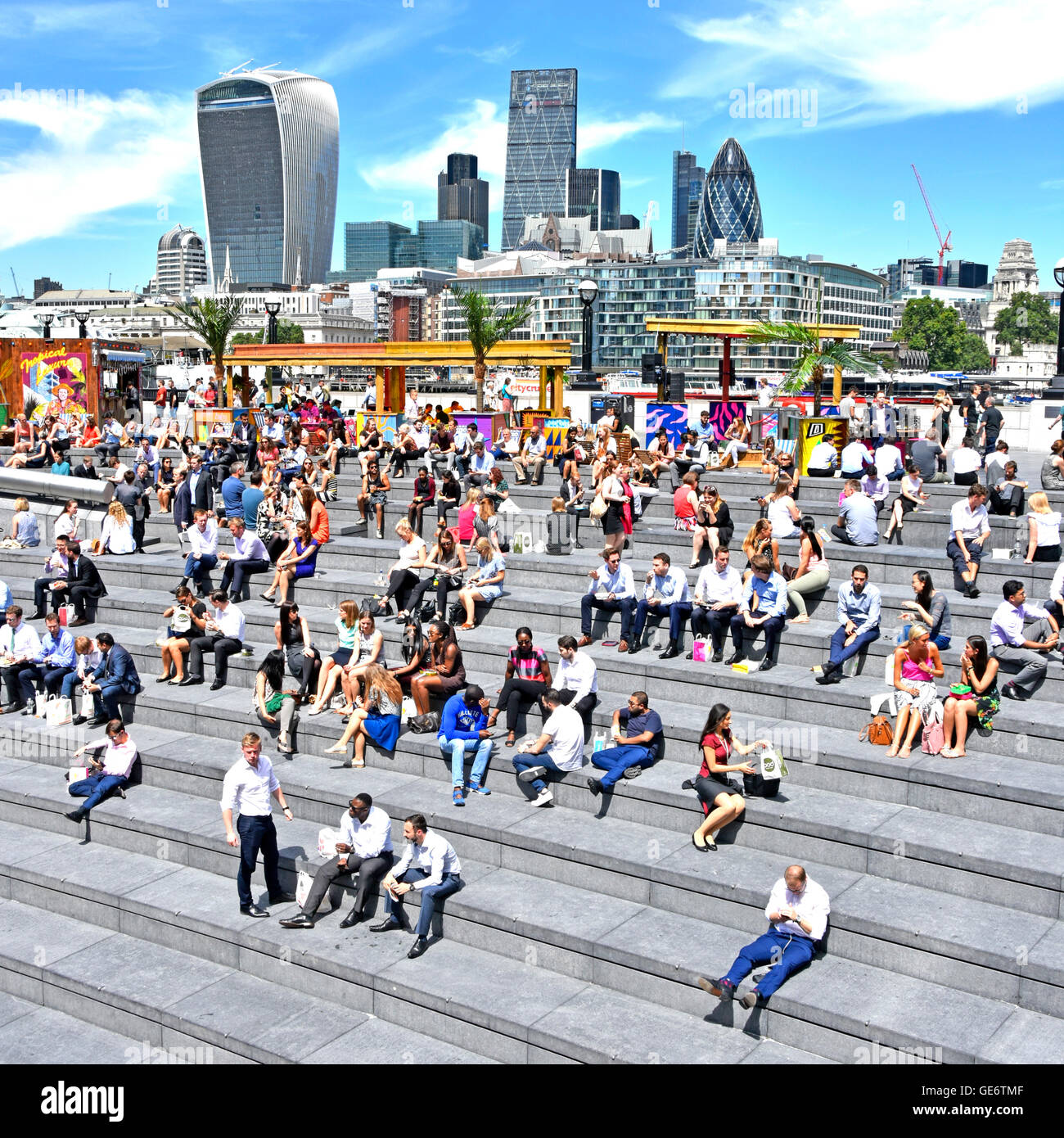 Southwark Büroangestellte nehmen heiße sonnige Mittagspause im Mehr London Scoop Amphitheater am Fluss mit City of London Skyline Über England hinaus Stockfoto