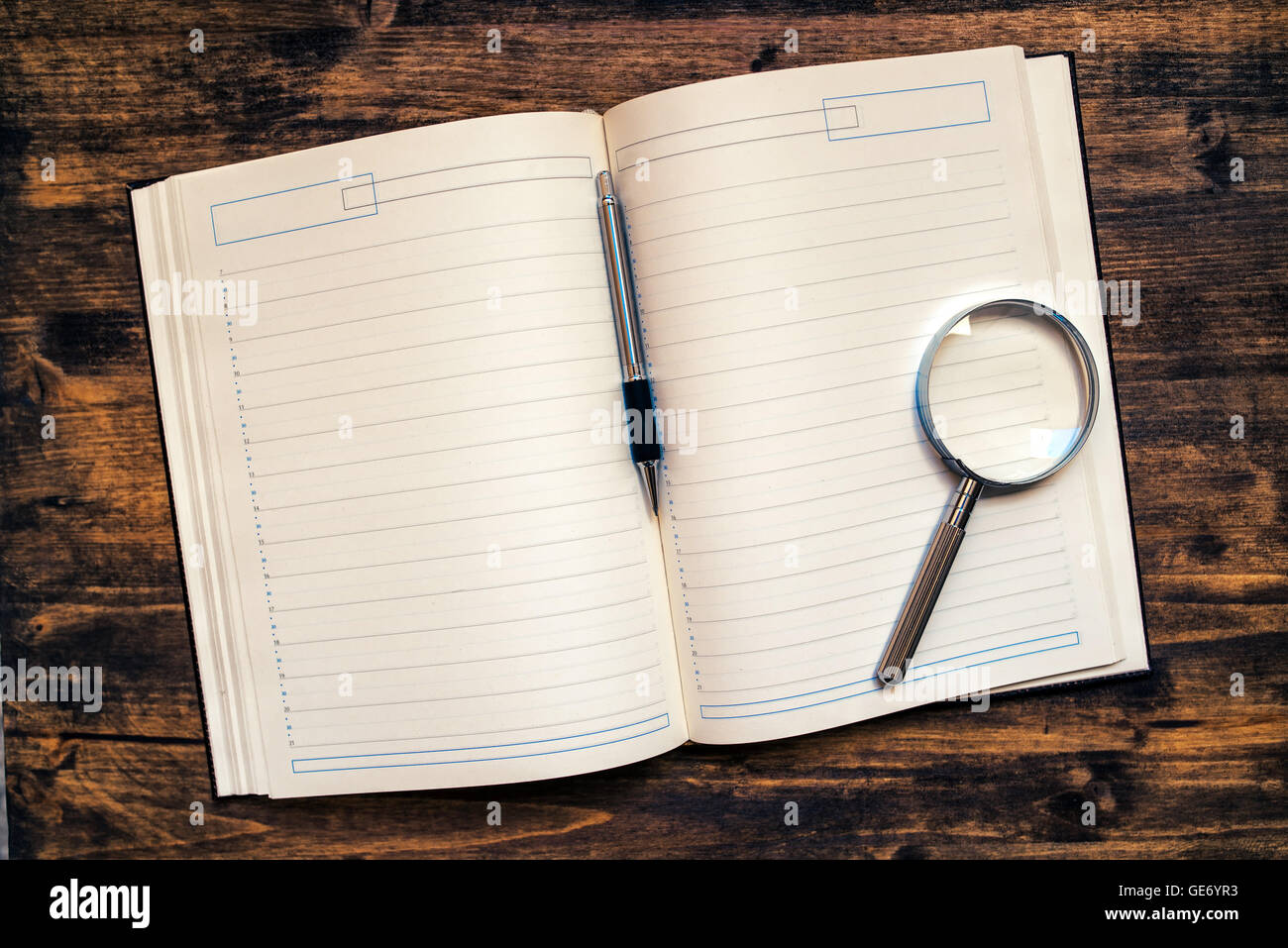 Unternehmen Termine Agenda Notizbuch mit Bleistift und Lupe auf Schreibtisch, Ansicht von oben mit Leerseiten als Textfreiraum Stockfoto