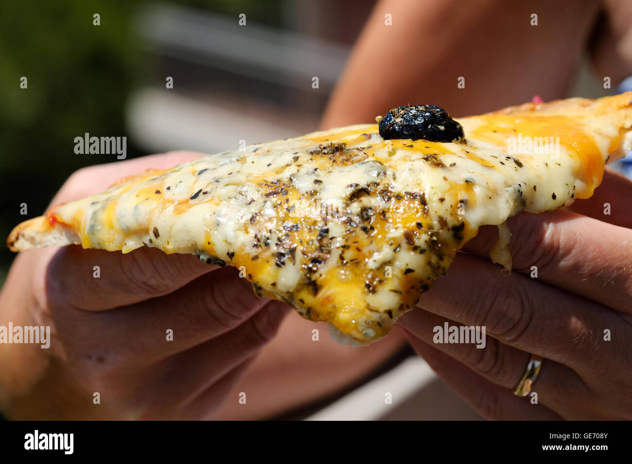 Jemand hält ein köstliches frisch gekochtes Stück Pizza vier Käse Stockfoto