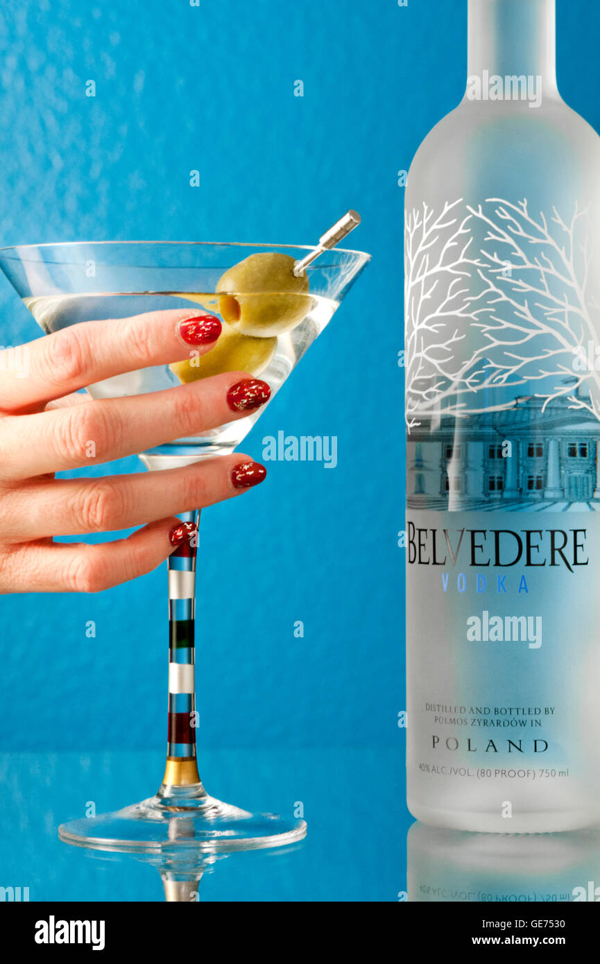 Belvedere Vodka und zwei Oliven Martini mit Frauenhand mit Glas Stockfoto