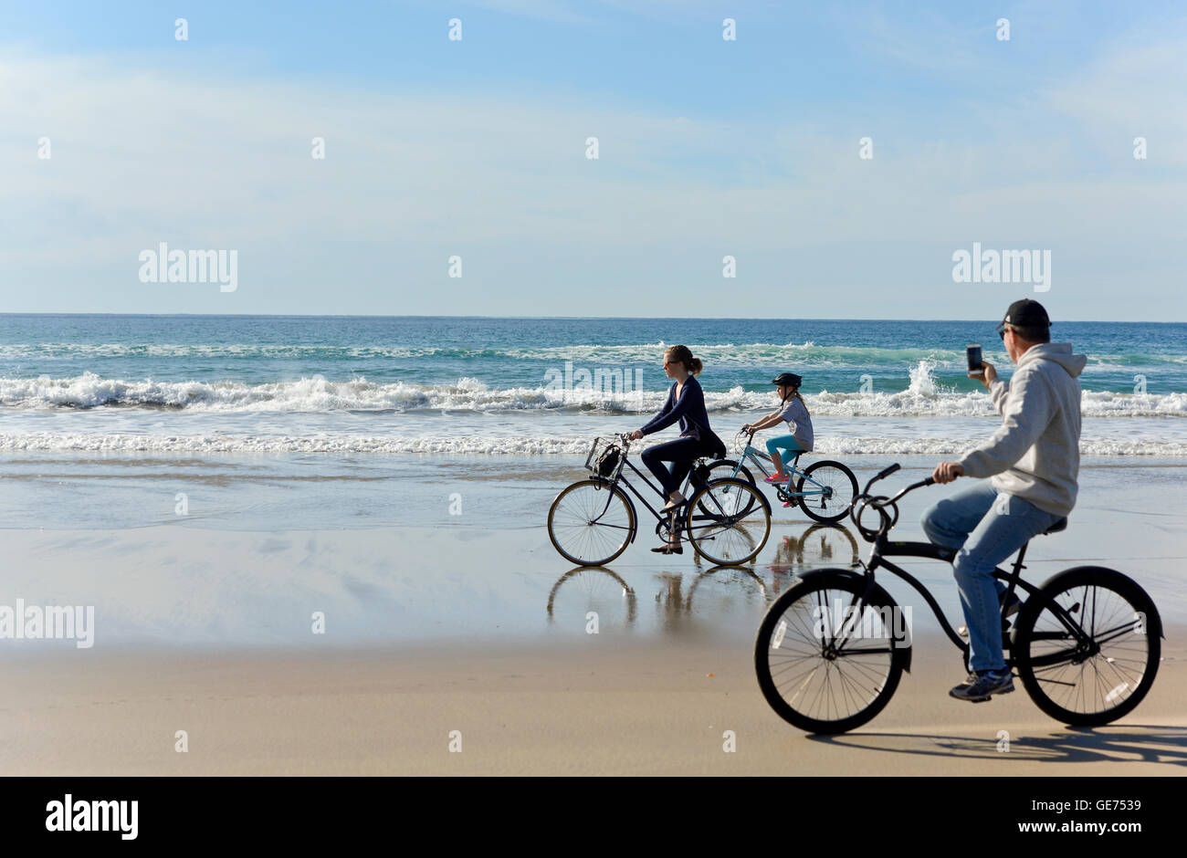Familie fährt Fahrrad am Strand, und Dad macht ein Handy-Video in San Diego, Kalifornien Stockfoto