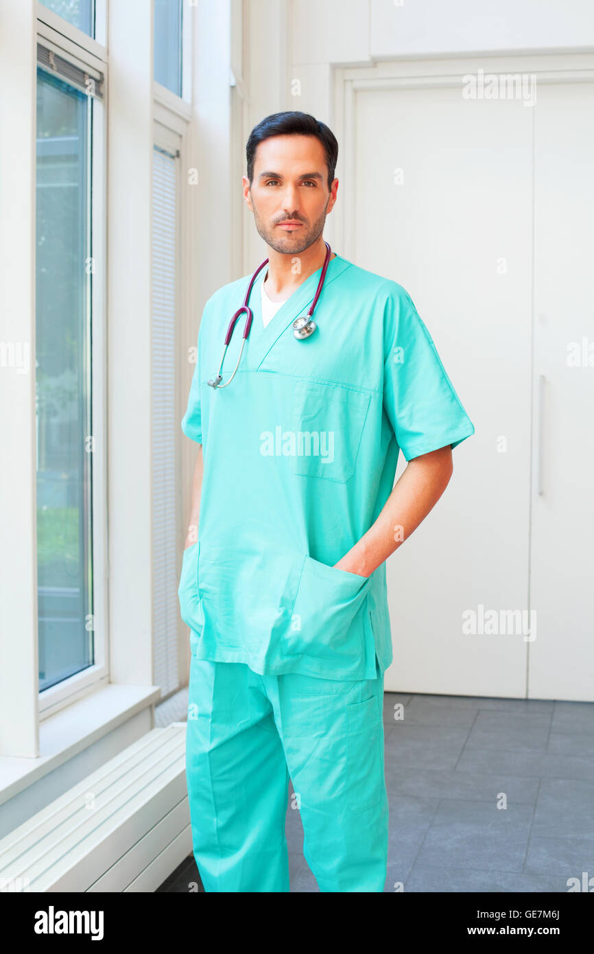 Porträt des männlichen Chirurgen stehend mit Hand in der Tasche. Zuversichtlich Arzt trägt scheuert. Er steht in dern Stockfoto