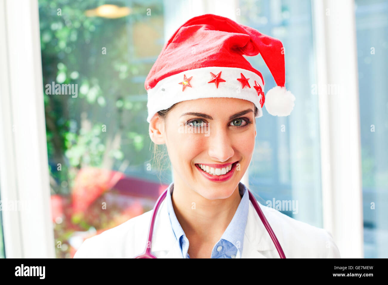 Porträt von glücklich Ärztin Santa Hut trägt. Schöne junge Arzt lächelt. Sie ist mit zuversichtlich Blick o Stockfoto
