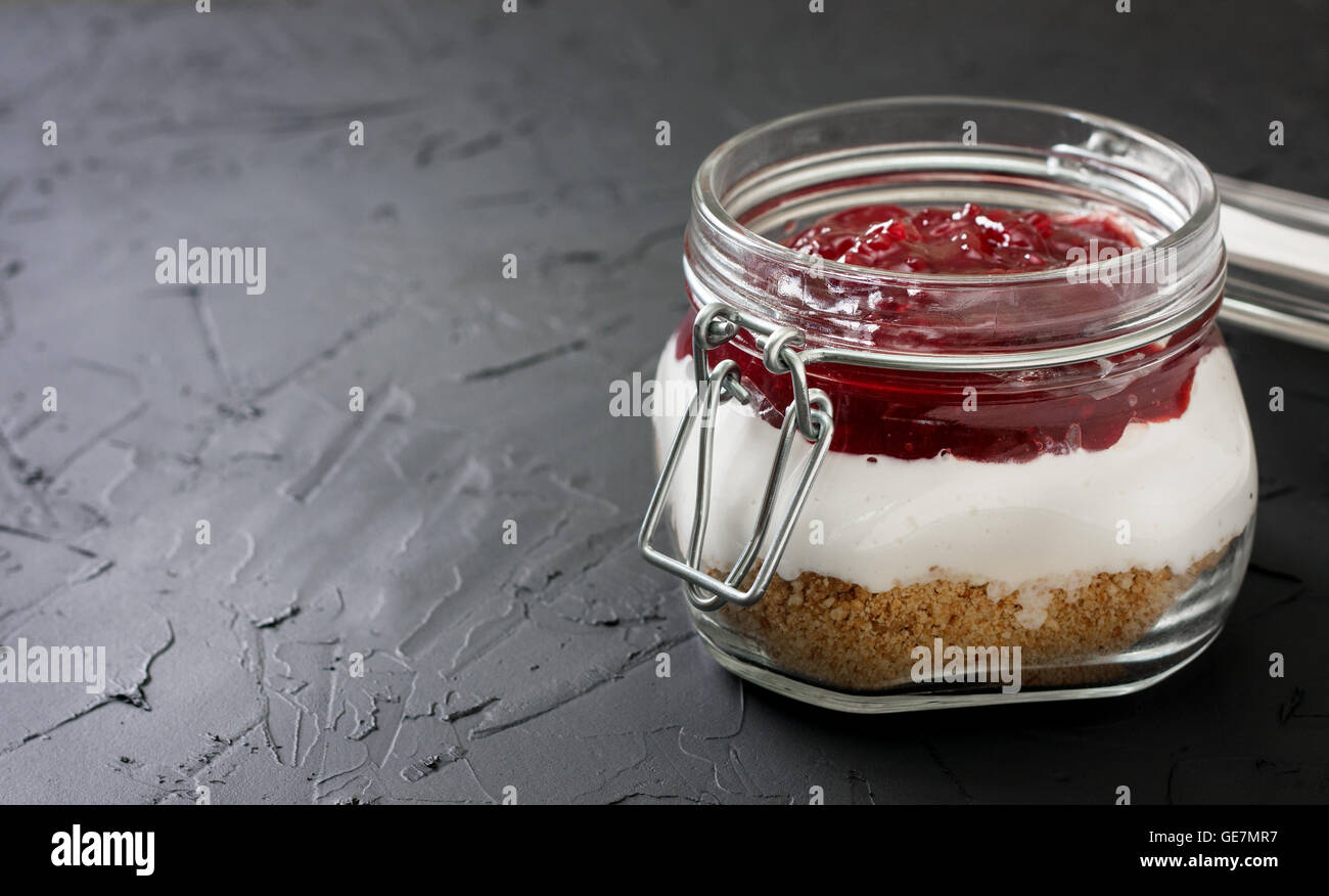 nicht Backen Käsekuchen mit Obstkonfitüre (Frucht) in einem Glas auf einem schwarzen Hintergrund konkrete Stockfoto