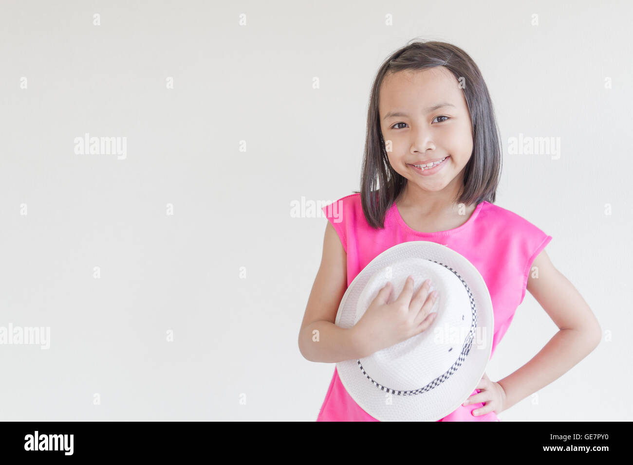 Entzückende glücklich asiatischen Kinder in einem rosa Kleid mit weißen Hut. Stockfoto
