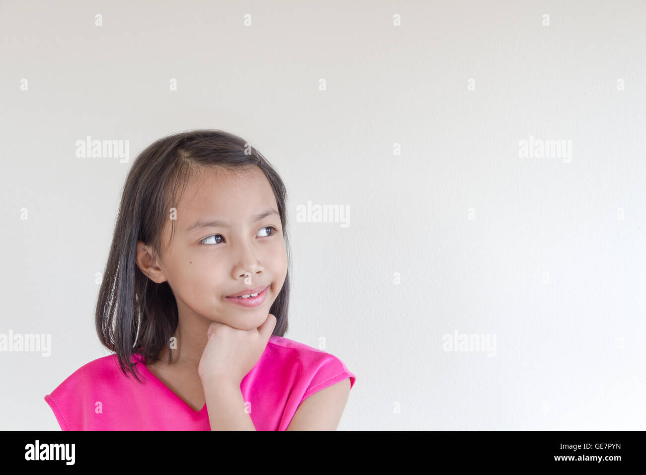 Entzückende asiatische Kinder in einem rosa Kleid mit weißen Hut auf der Suche nach etwas Stockfoto