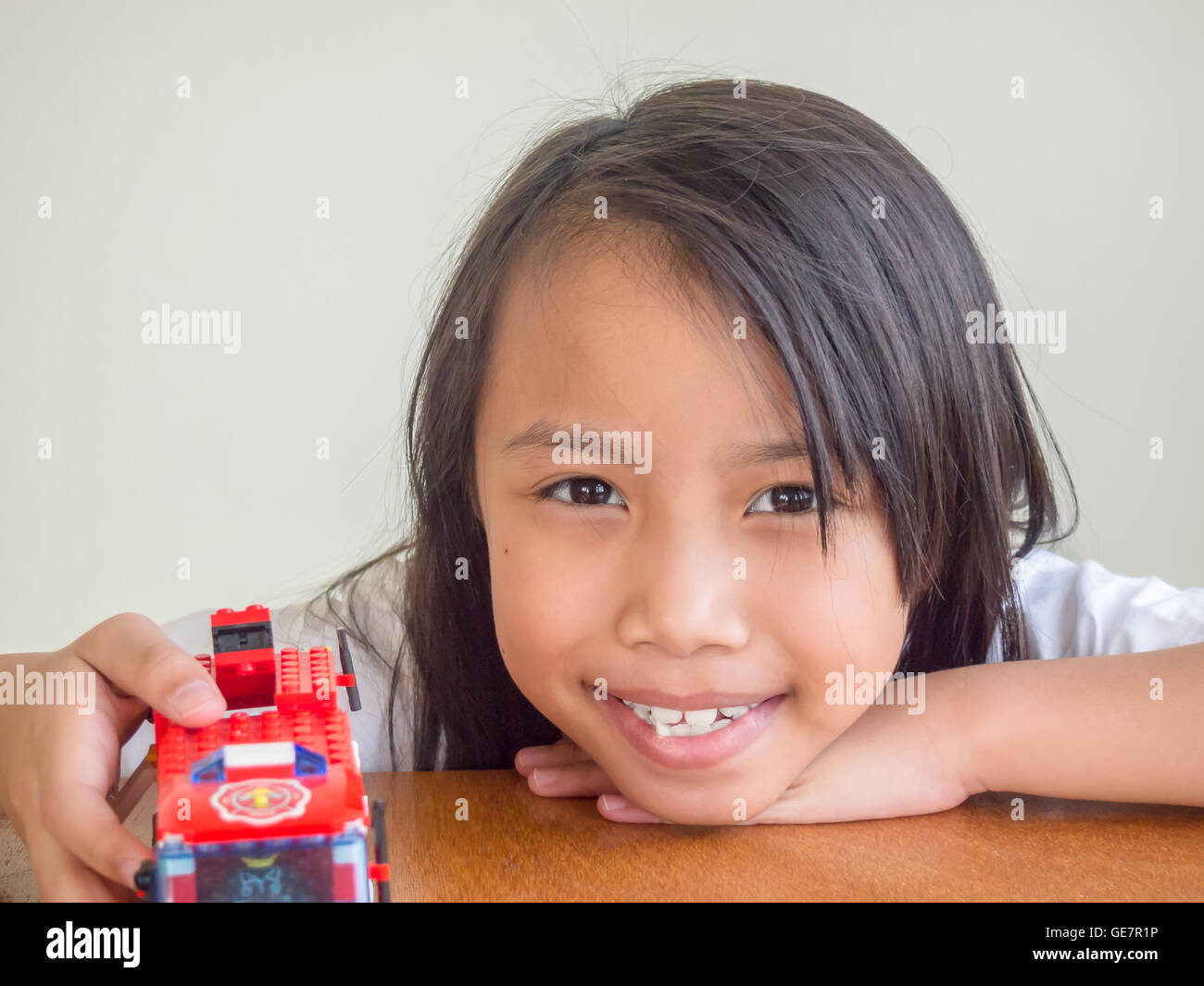 Kleine Asiatin eine Spielzeug zu spielen und sitzen auf dem Holztisch Stockfoto