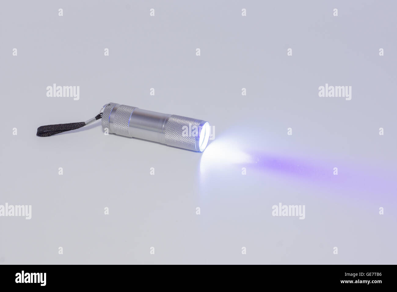 kleine Taschenlampe arbeiten auf einem weißen Hintergrund mit einem Strahl von Licht Stockfoto