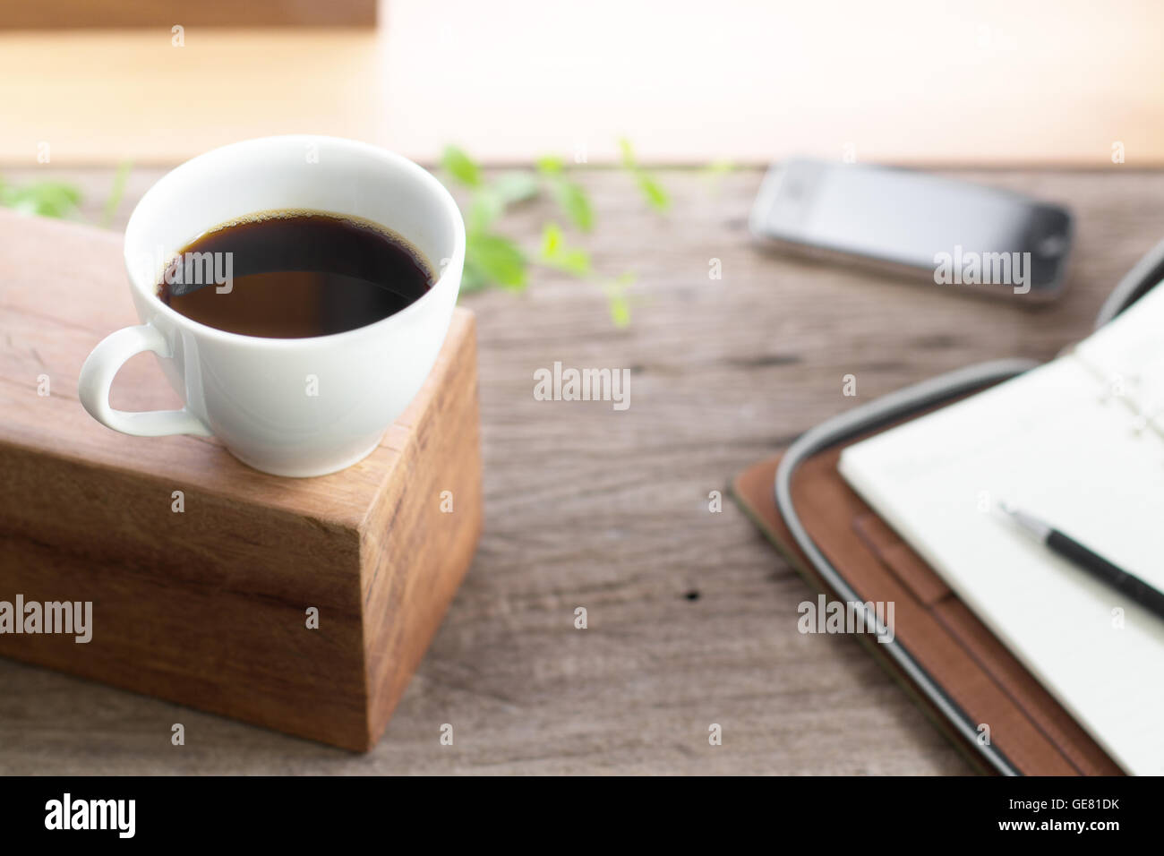 weiße Tasse Kaffee mit Hinweis Buch Smartphone auf Holzplatte Tabelle isolierten hellen Hintergrund Stockfoto
