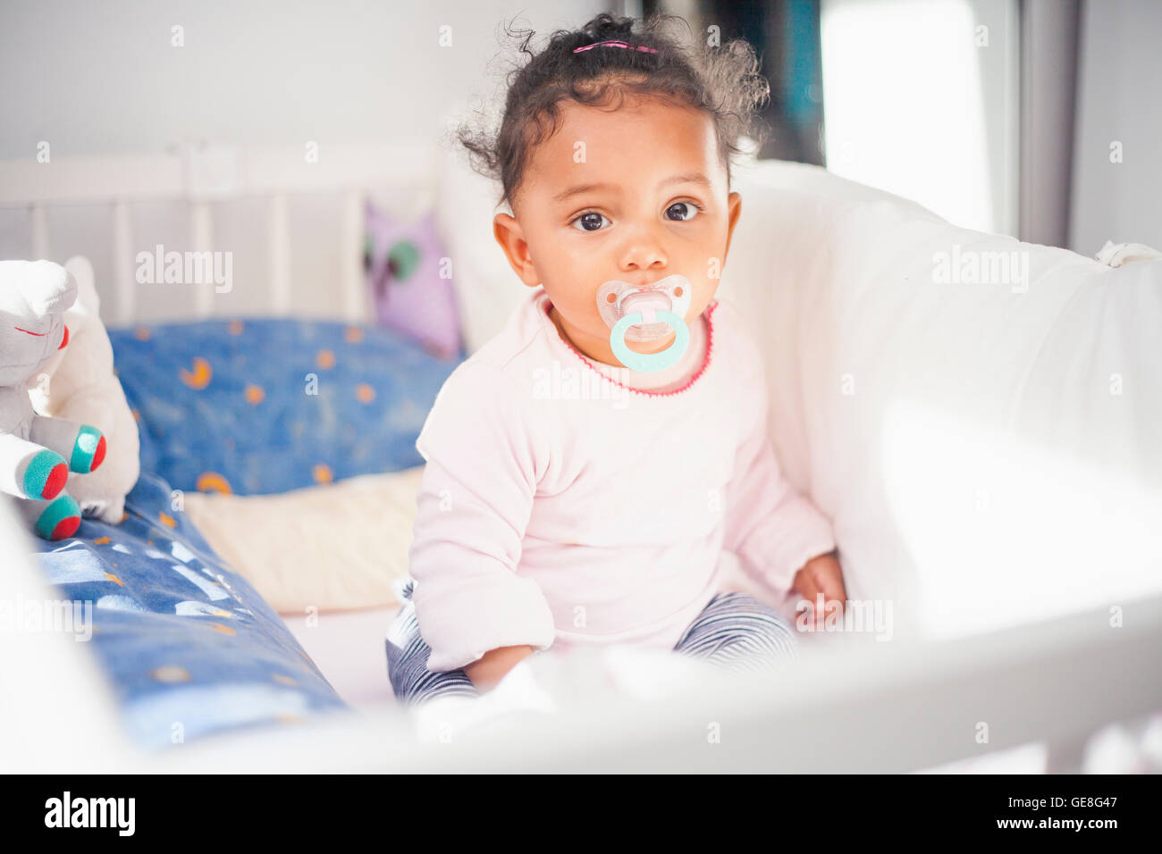 Porträt von müde Baby Girl mit Schnuller im Bett sitzen Stockfoto