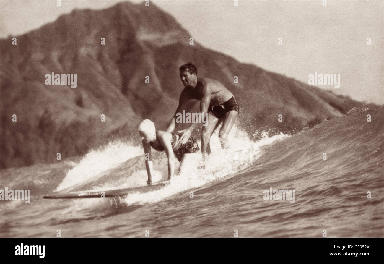 Tom Blake und Odetta Bray tandem Surfen in den 1930er Jahren im Waikiki in Honolulu, Hawaii mit Diamond Head im Hintergrund. Stockfoto