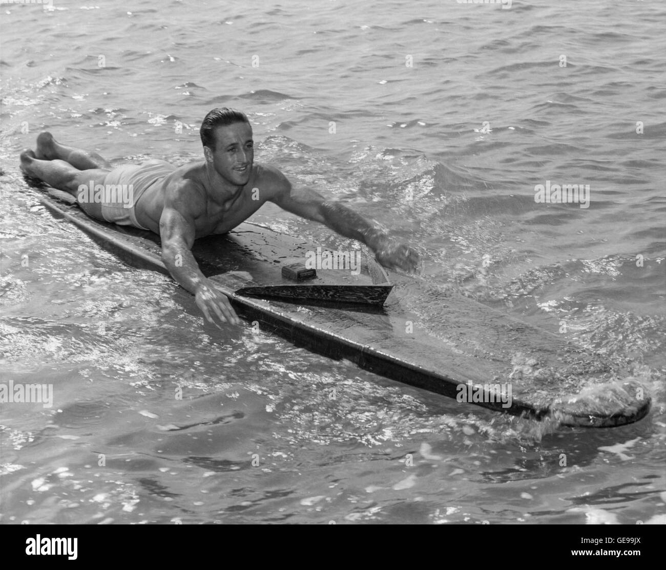Champion Surfer/Paddler Gene "Tarzan" Smith auf hölzernen Surfbrett während fast 100 Mile Paddel von Honolulu nach Kauai (Hawaii-Territorium). Smith ging auf seine Welt Rekord Paddel am 14. Oktober 1940 von Oahu Kaena Point auf einem Surfbrett 14 Fuß in Bereichen der raue Brandung in Richtung zu seinem Bestimmungsort auf der Insel Kauai, 90 Meilen entfernt. Nach 30 Stunden Paddeln über was als einer der gefährlichsten Kanäle in der hawaiischen galt Gewässern, Gene in Koloa angekommen, ungefähr fünf Meilen westlich von seinem Ziel, Nawiliwili Hafen, dass Kurs von starken Winden weggeblasen. Stockfoto