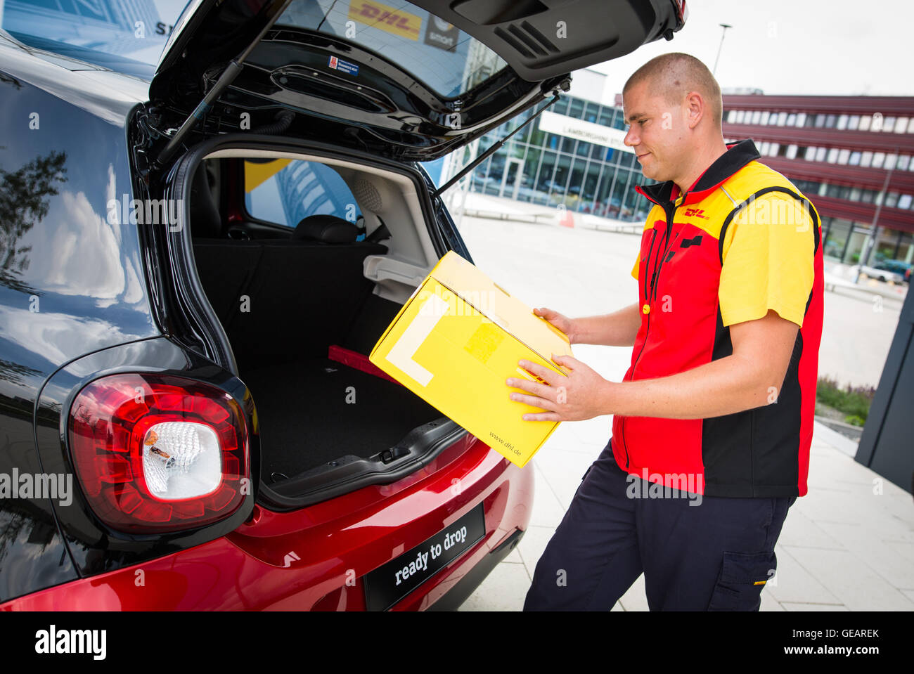 Böblingen, Deutschland. 25. Juli 2016. Ein DHL-Bote stellt eine Paket in den Kofferraum eines Smart Autos in Böblingen, 25. Juli 2016. Intelligente und DHL planen Stamm Lieferung. Paket-Träger werden in der Lage, Pakete an den Stämmen des Kleinwagens mit Key-Less-Technologie zu liefern. Foto: Christoph Schmidt/Dpa/Alamy Live News Stockfoto