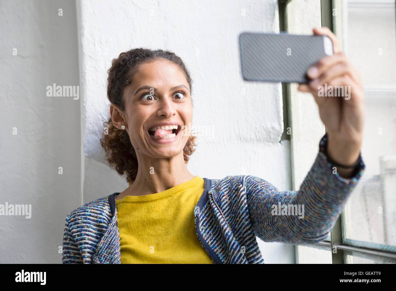 Junge Frau steht am Fenster nehmen Selfie mit Smartphone Stockfoto
