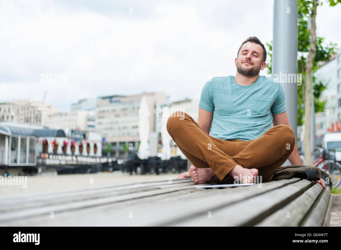 Entspannte junger Mann im Freien sitzen auf Bank Stockfoto