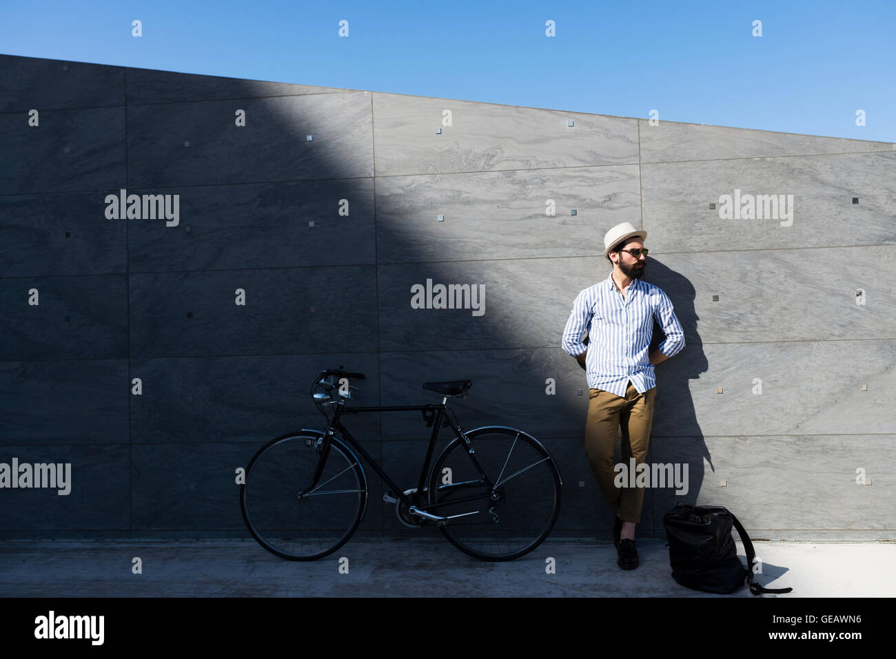 Junger Mann mit Fahrrad und Rucksack Wand gelehnt Stockfoto