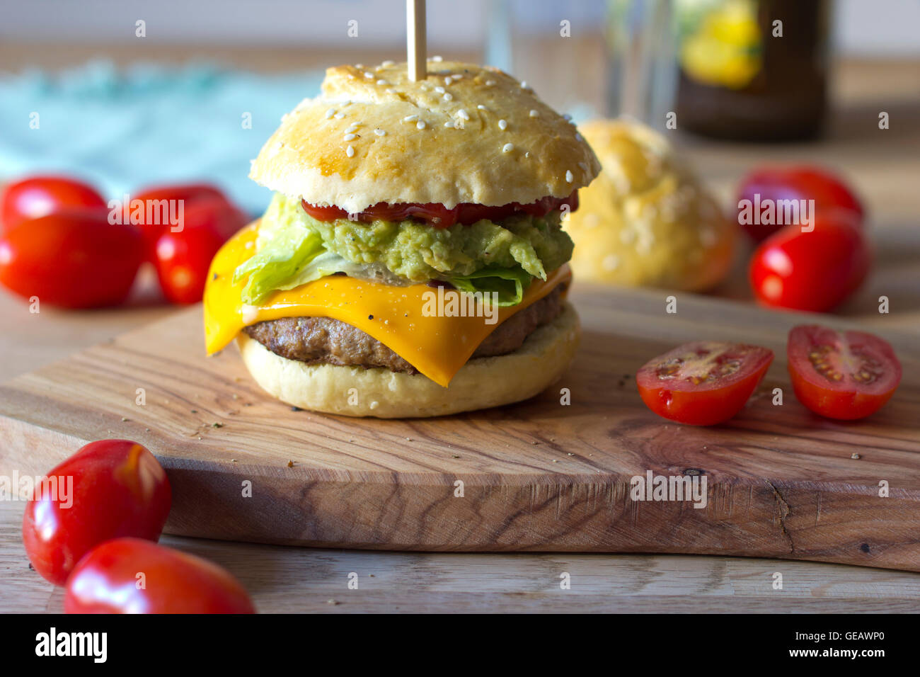 Sesam Brötchen mit Burger, Avocado Creme, Salat, Ketchup und Tomaten Stockfoto