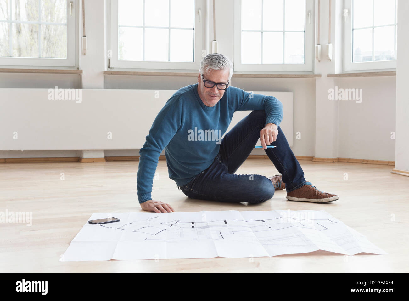 Mann im Bauplan in leerstehenden Wohnung suchen Stockfoto