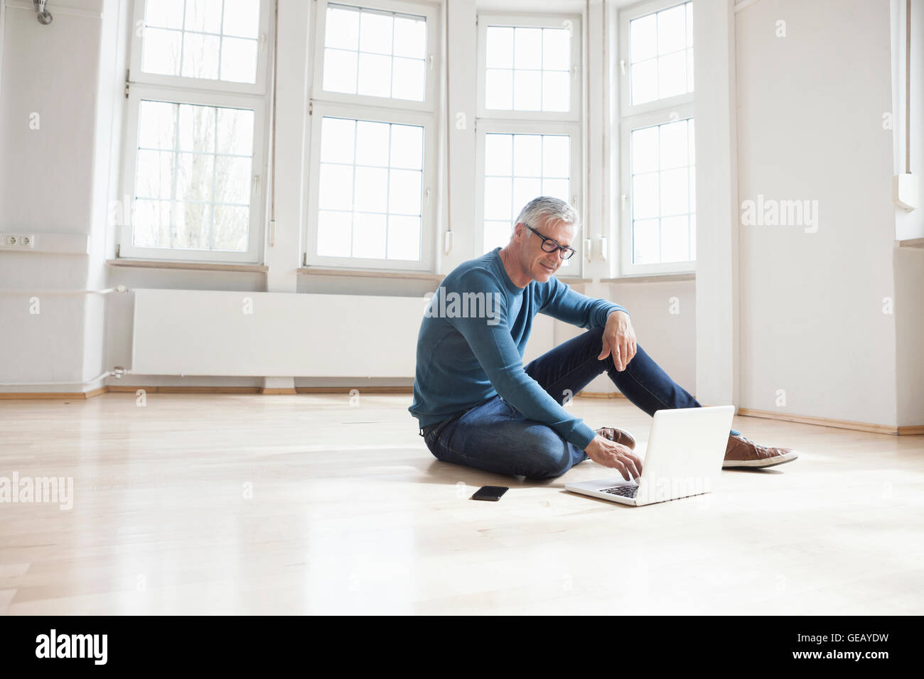 Mann mit Laptop in leere Wohnung Stockfoto