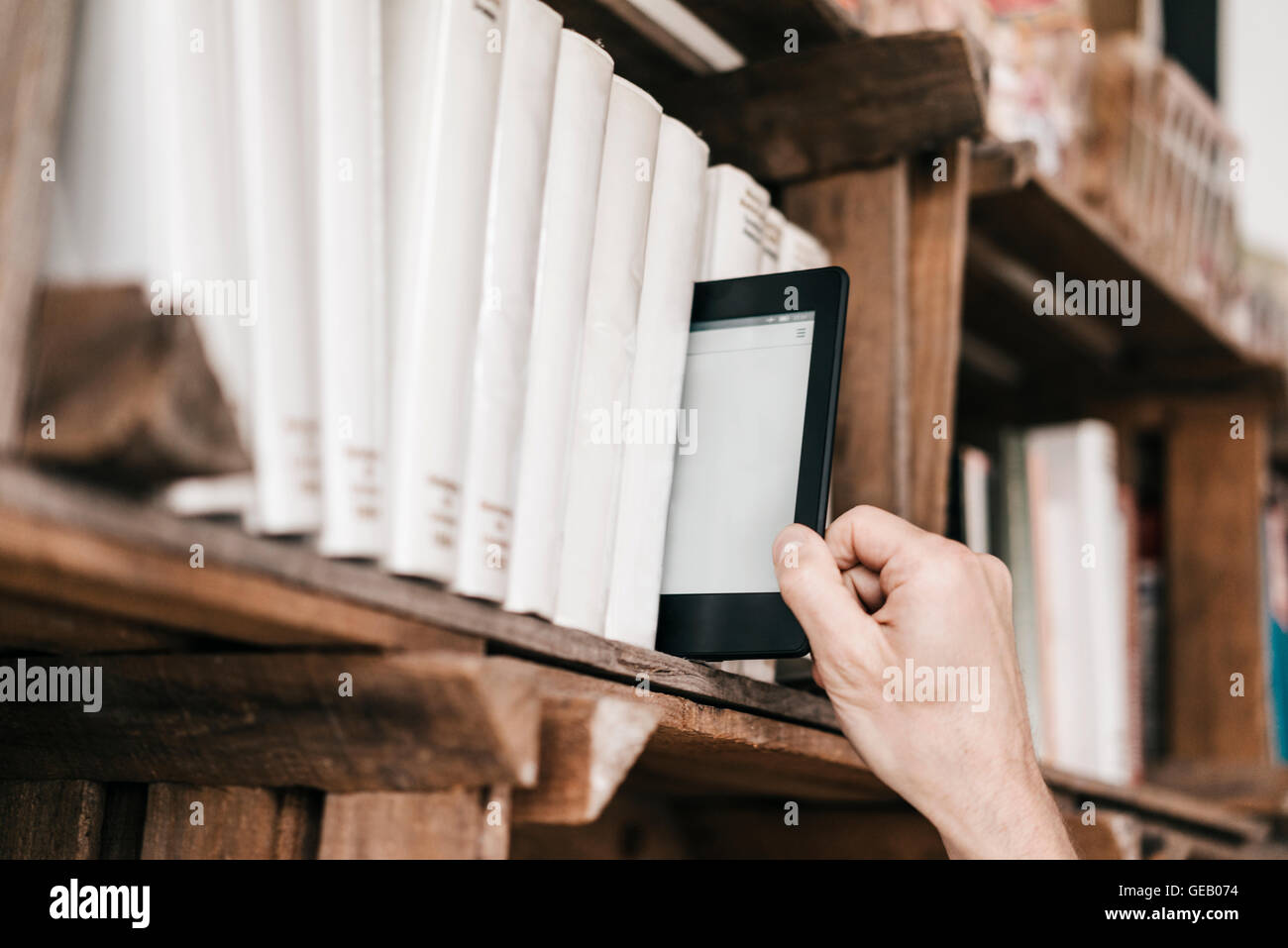 Hand unter e-Book von Bücherregal Stockfoto