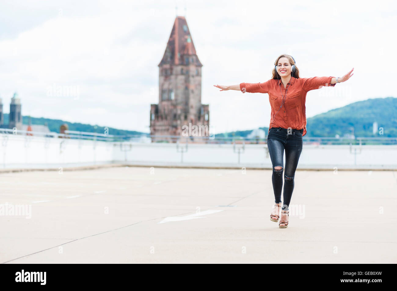 Deutschland, Saarbrücken, Frau Musik hören mit Kopfhörern tanzen auf der Dachterrasse Stockfoto