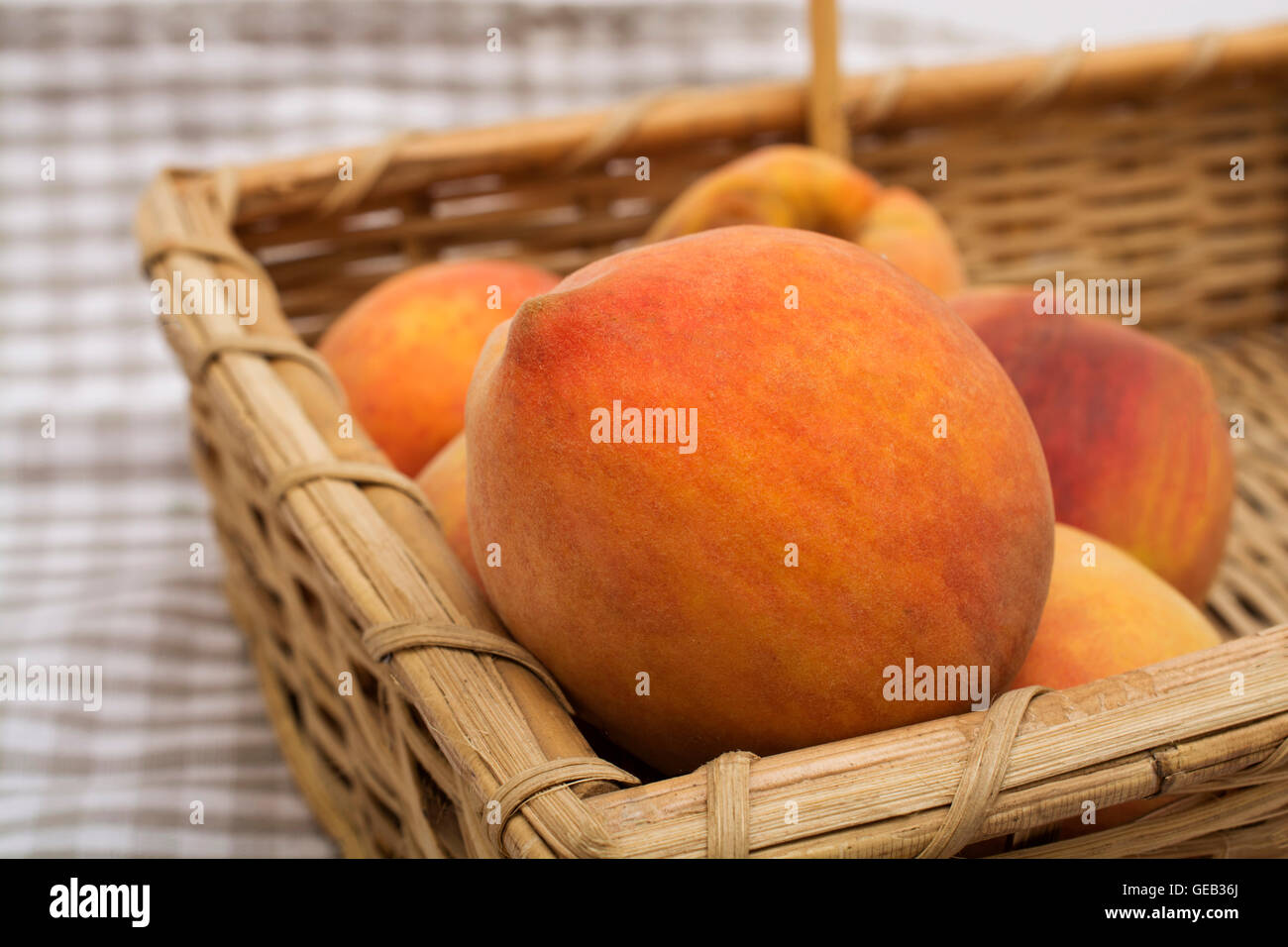 Reife Pfirsiche Obst im Korb auf einer Tischdecke. Stockfoto