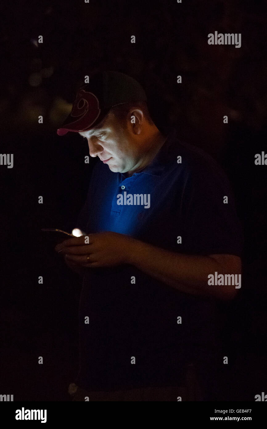 Ein Mann spielt Pokemon gehen auf seinem Handy in der Nacht. Stockfoto