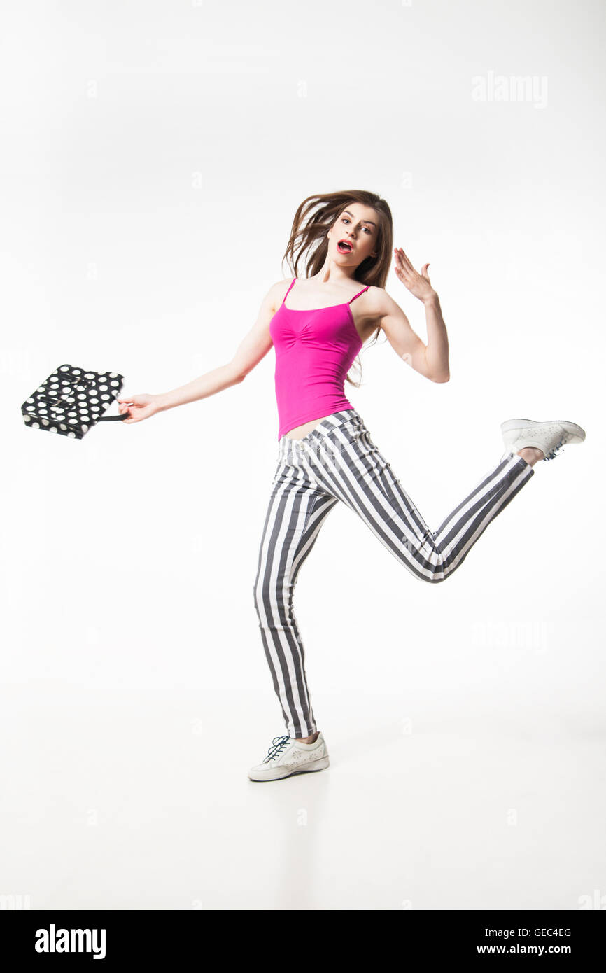 Brunette Modell sprang mit Bein und halten Polka Dot Tasche Stockfoto